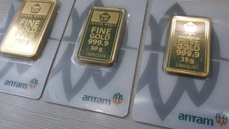Tiga kepingan emas batangan Logam Mulia Antam kemasan CertiCard pecahan 100 gram, 50 gram, dan 25 gram di atas meja