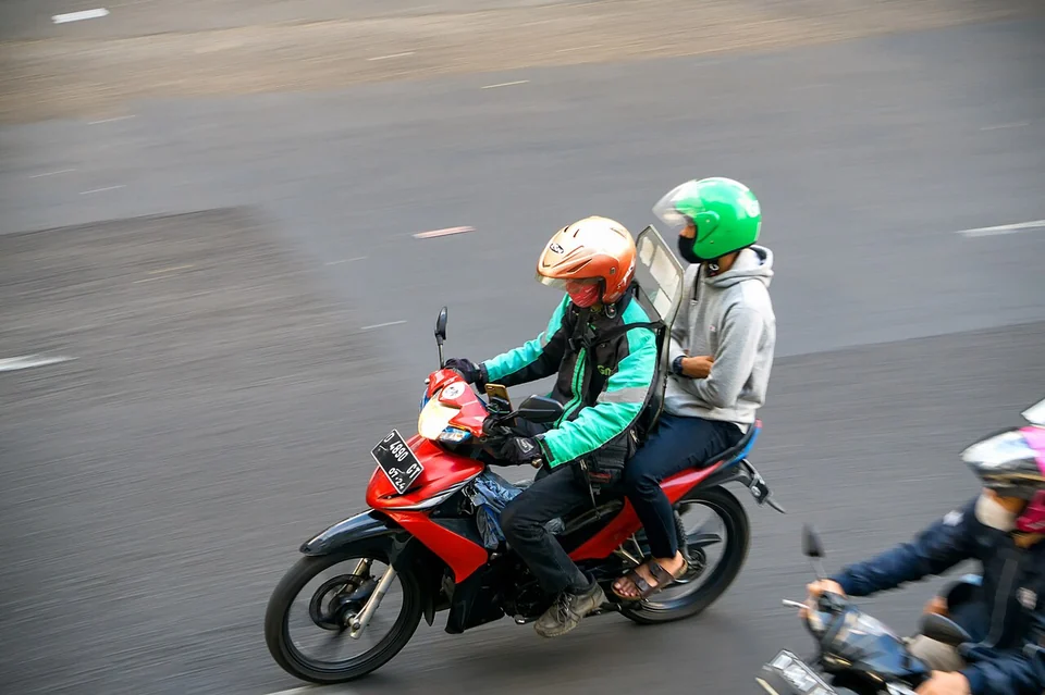 Driver ojek online melintas di jalan - side job untuk karyawan kantoran