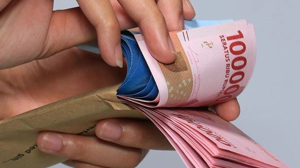 Pekerja menghitung uang tunai Rupiah di meja kerja sebagai ilustrasi cara mengatur gaji 5 juta