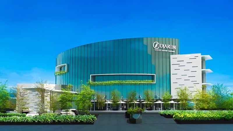 Gedung kantor PT Djarum dengan fasad kaca berwarna biru kehijauan dan logo Djarum terpasang di sisi kanan bangunan