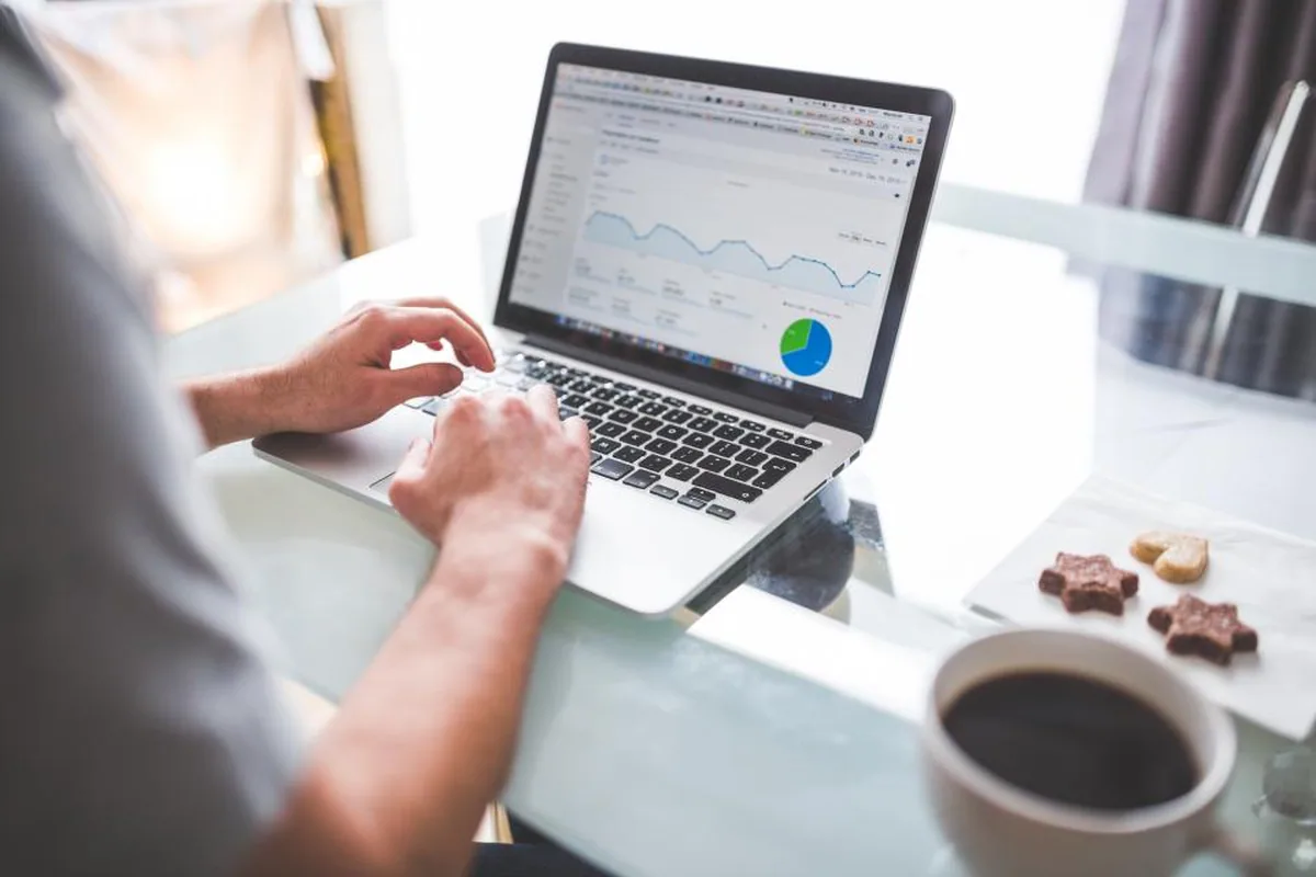 Laptop menampilkan grafik saham dengan catatan analisis di sampingnya