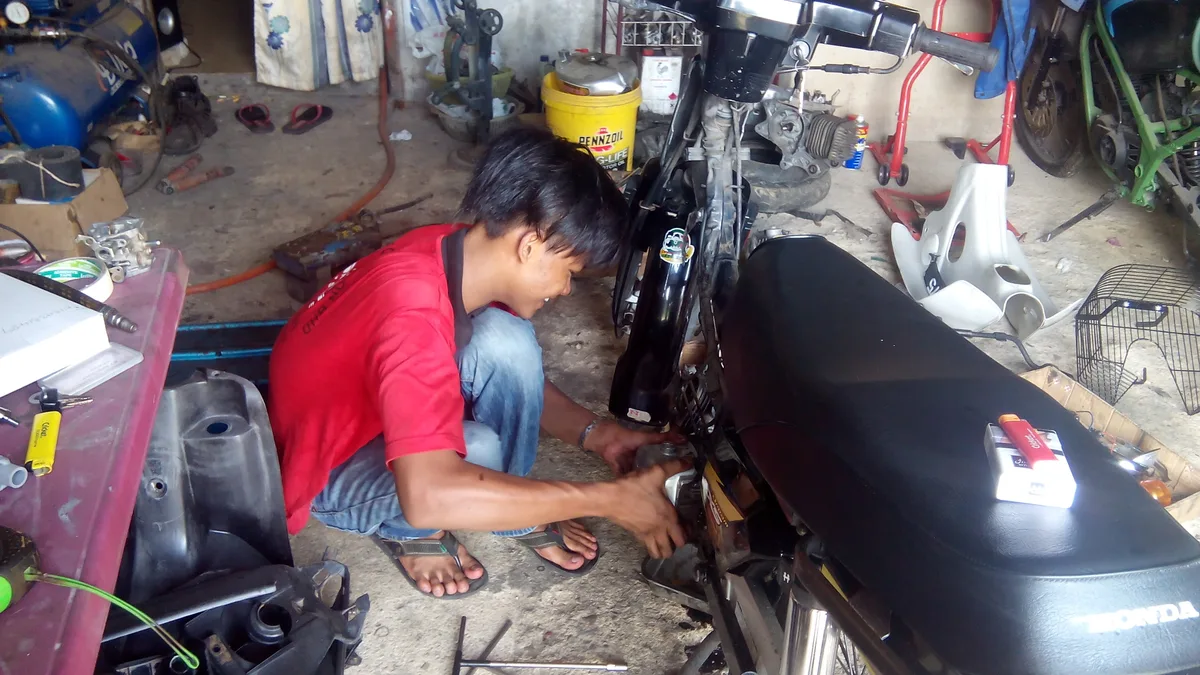 Mekanik sedang melakukan perbaikan kendaraan dan penggantian suku cadang di bengkel