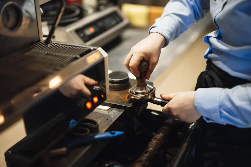 Barista menyiapkan espresso menggunakan mesin espresso profesional di coffee shop