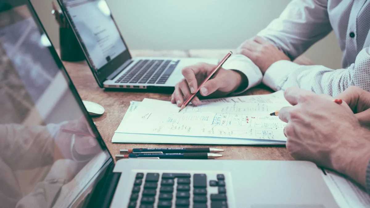 Profesional akuntan dan analis keuangan memeriksa dokumen laporan keuangan dan laptop di meja kerja