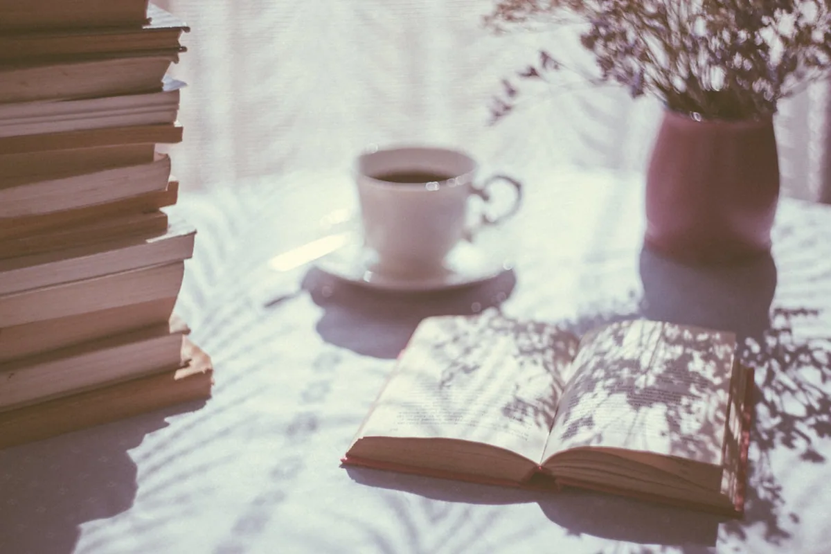 Buku psikologi uang terbuka di meja baca dengan kopi dan catatan keuangan